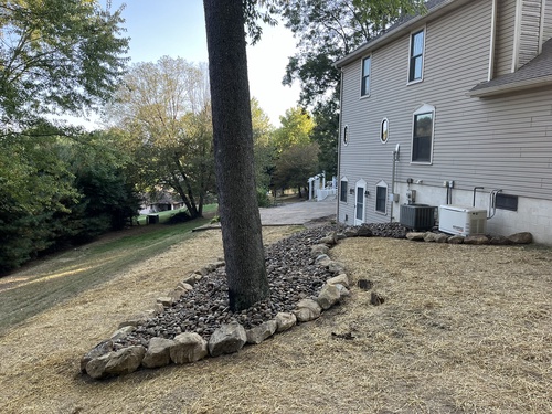 Stone bed installed around a mature tree at a Tuscarawas County property