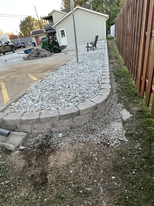 Block retaining wall and drainage rock installed along a driveway
